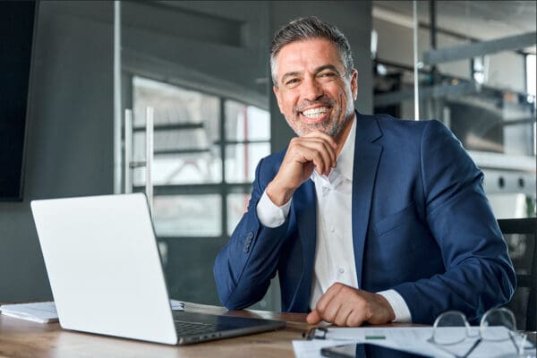 Happy middle aged business man ceo working on laptop sitting in office