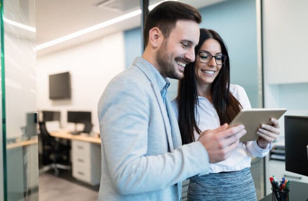 Attractive business couple using tablet in modern office