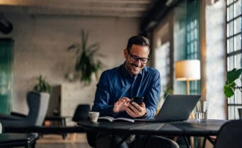 Photo of a smiling man using a mobile phone while